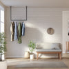 Tringle à vêtements minimaliste noire suspendue au plafond dans l'entrée de la maison