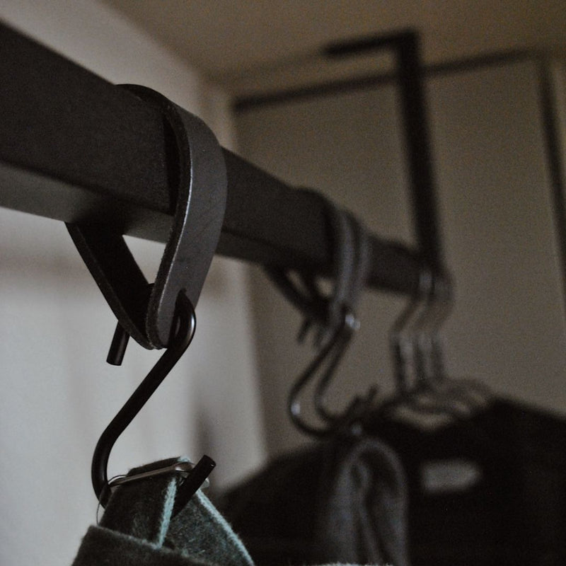 Portant à vêtements noir suspendu au plafond avec crochets en cuir pour suspendre casquettes, écharpes et manteaux