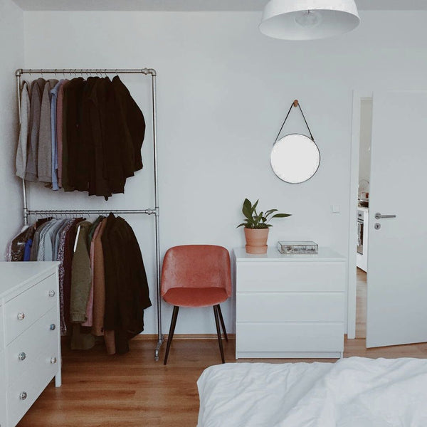 portant à vêtements autonome en tuyaux argentés dans une chambre à coucher