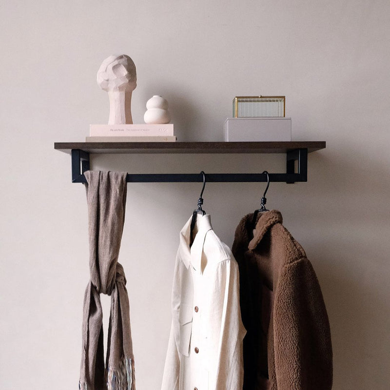 étagère en chêne fumé équipée d'une tringle à vêtements minimaliste noir mat pour suspendre les vestes 