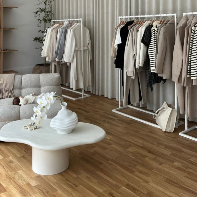 Portant à vêtements minimaliste blanc avec socle carré pour aménager un magasin